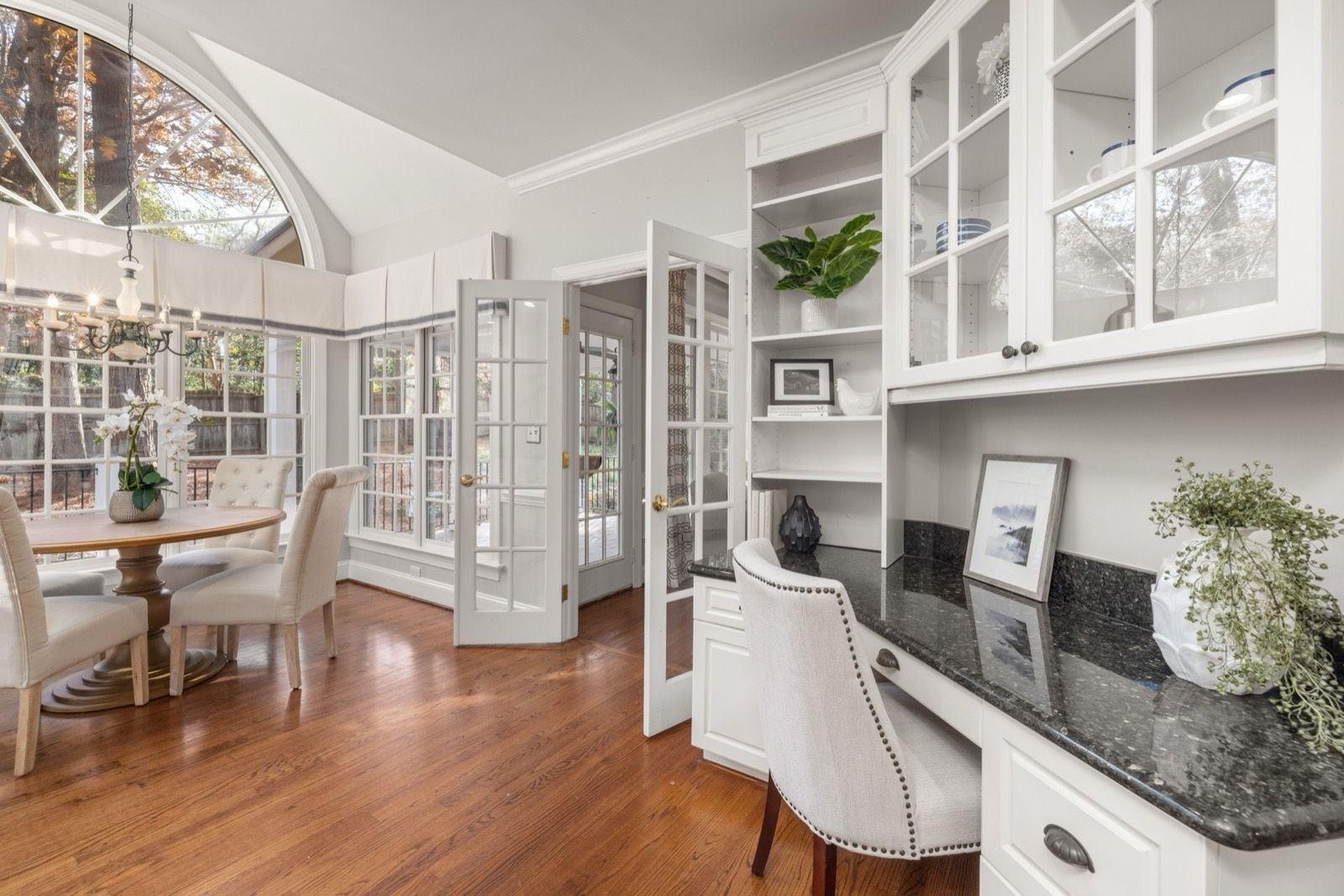 Bright room with white painted built-in cabinets, French doors and crown molding beside a round dining table