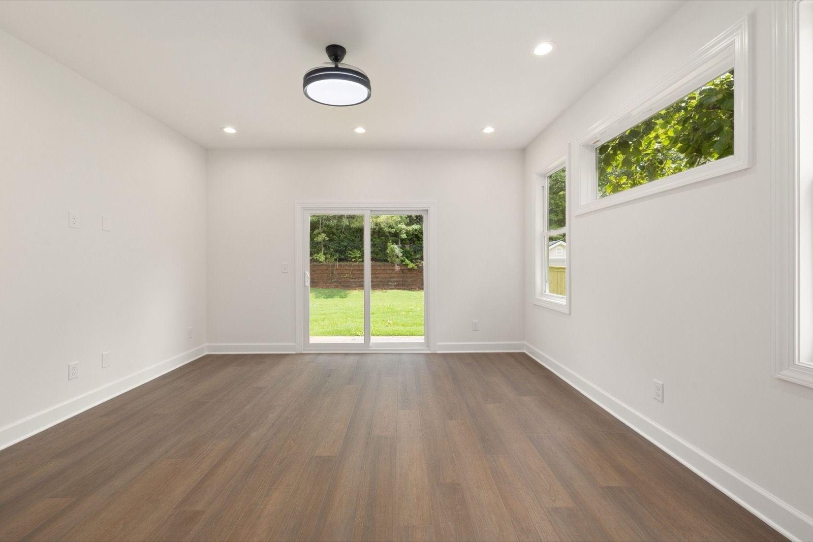 Bright empty room with smooth white walls, crisp white baseboards and window trim, and a sliding glass door
