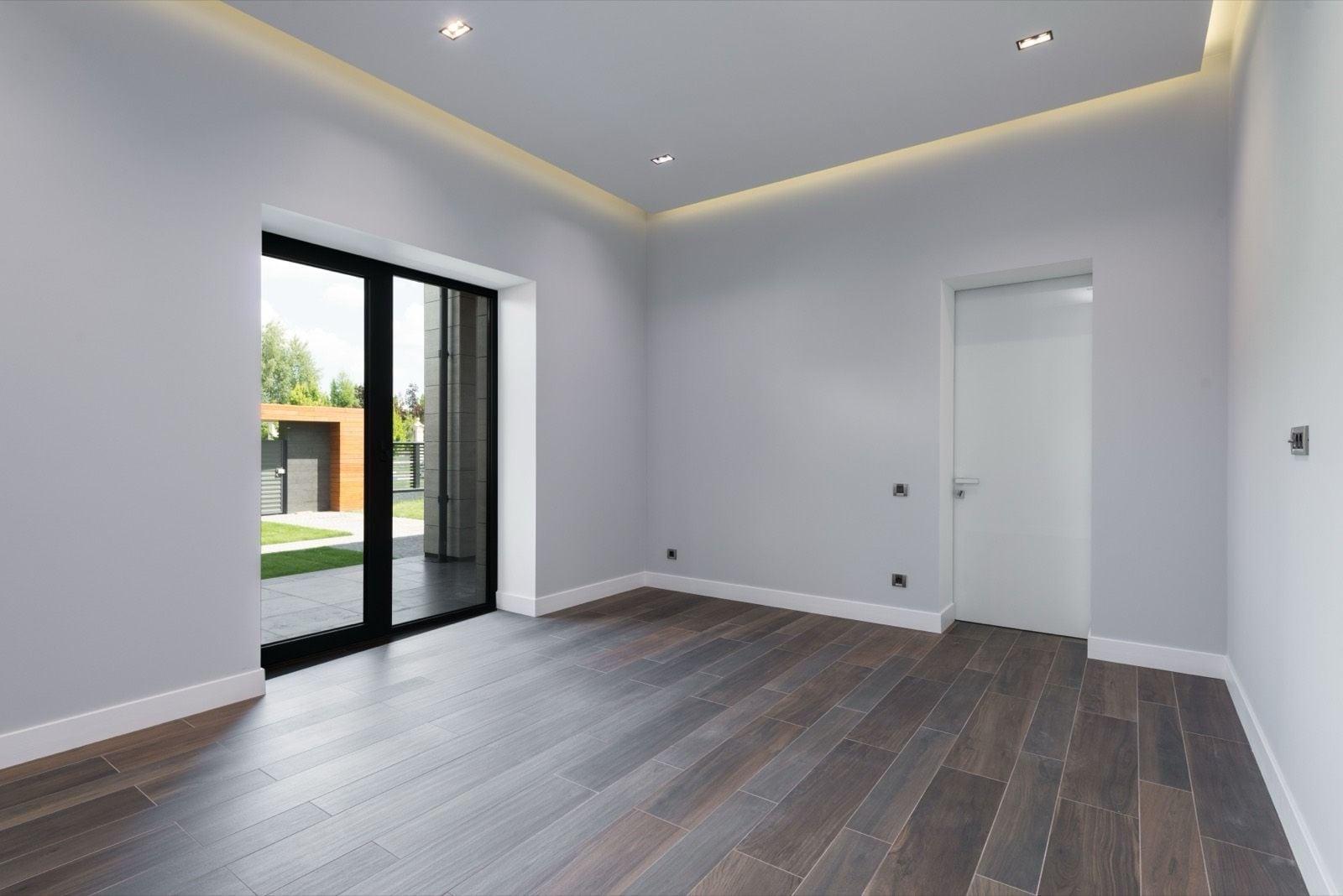 Empty modern room with smooth light gray walls, white baseboards and a white flush door beside a sliding door