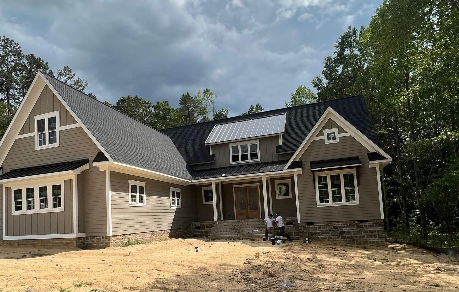 Taupe siding with white trim on a new craftsman-style home under a cloudy sky