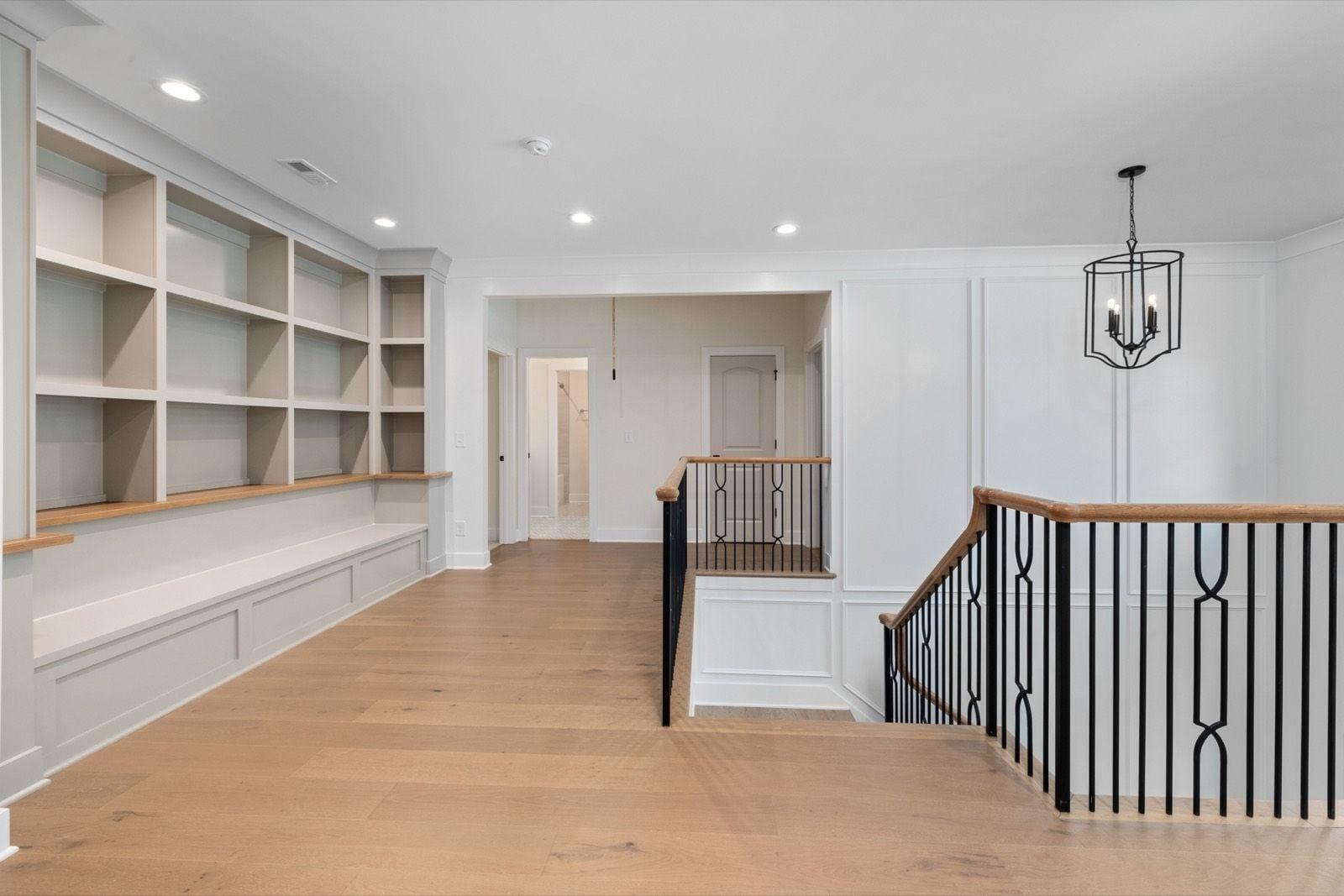Upstairs landing with painted built-in shelving, white paneled walls and a black iron stair railing