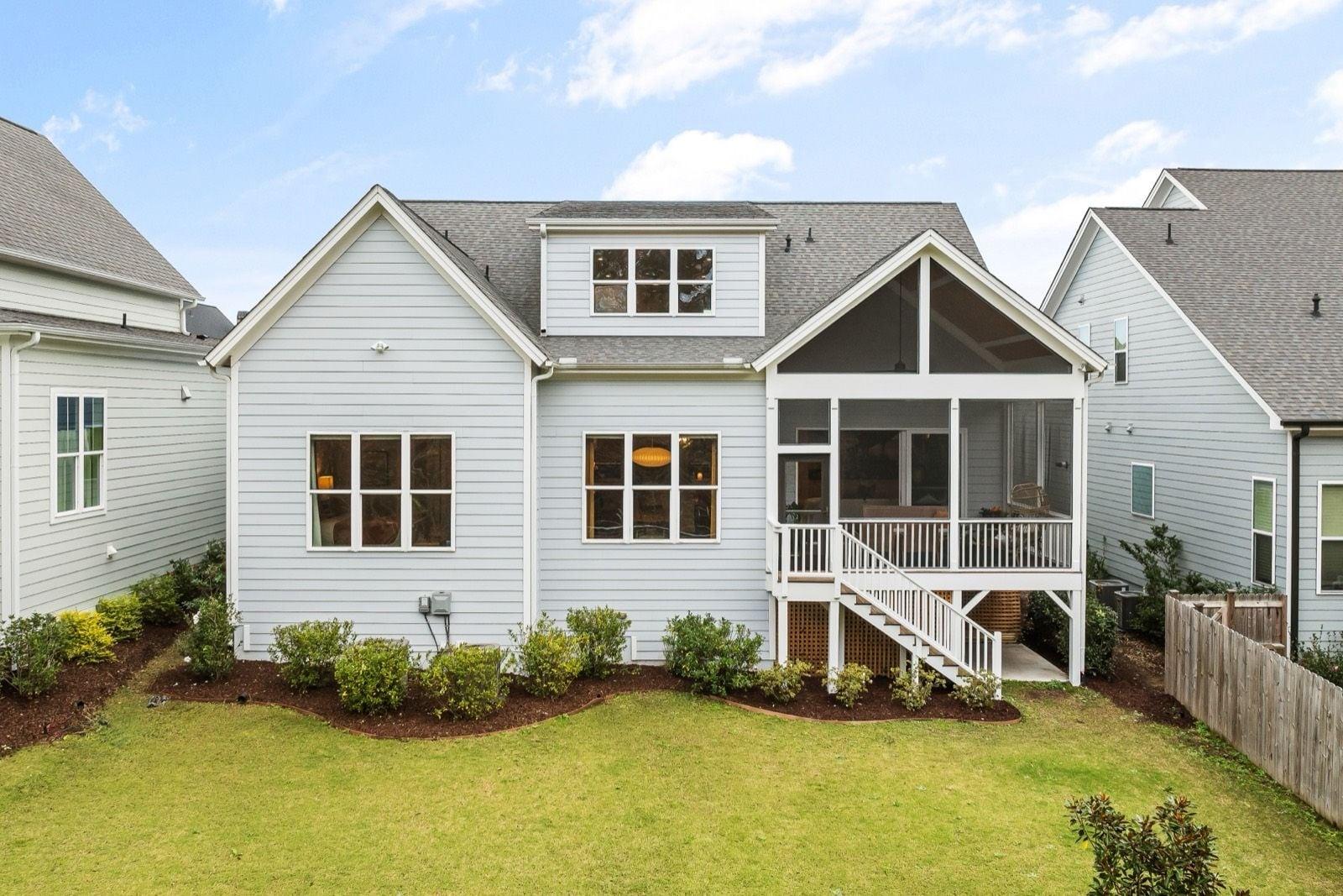 Light blue-gray lap siding with crisp white trim and railings on a home with a screened porch